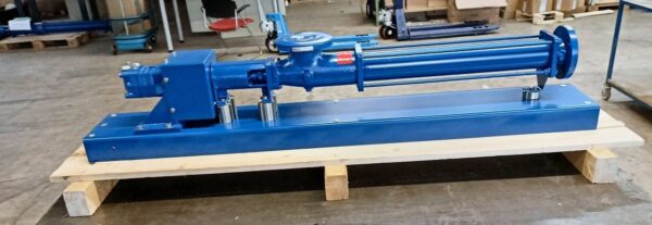 A blue Fludyn BEH 1024 progressive cavity pump / mono pump, aligned on a base plate, without motor, mounted on a wooden pallet for shipment. Workshop equipment can be seen in the background.