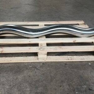 Ein blank polierter Rotor aus Metall liegt quer auf einer Holzpalette. Er ragt an beiden Seiten über die Palette hinaus so dass man seine Größe erkennen kann. Rechts ist der Anschluss für das Gelenk zu sehen.