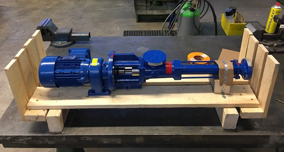 A blue Fludyn monopump / eccentric screw pump in an open shipping crate with various tools in the background