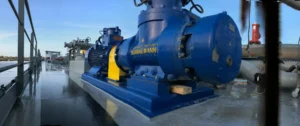 A large blue screw pump mounted on a barge